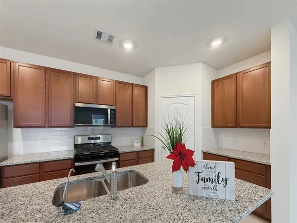 a kitchen with stainless steel appliances granite countertop a sink a stove cabinets and wooden floor