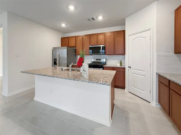 a kitchen with stainless steel appliances granite countertop a refrigerator stove microwave sink and cabinets