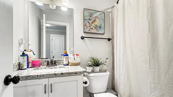 a bathroom with a granite countertop sink vanity mirror and toilet