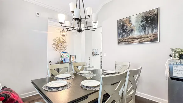 a view of a dining room with furniture a chandelier and wooden floor