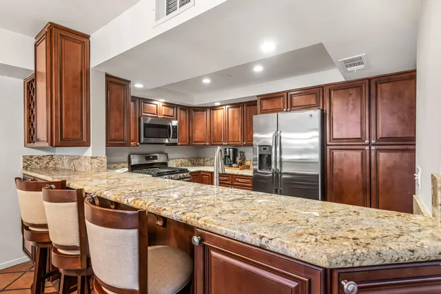 a kitchen with stainless steel appliances granite countertop a sink refrigerator and microwave