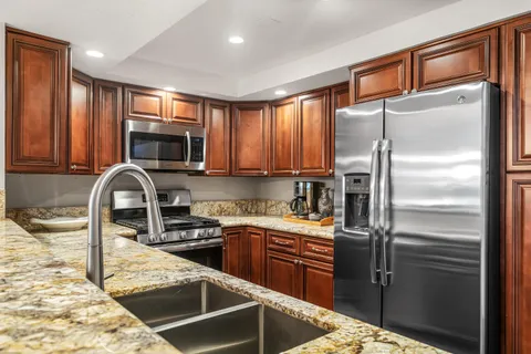 a kitchen with stainless steel appliances granite countertop a refrigerator a stove a sink and a microwave