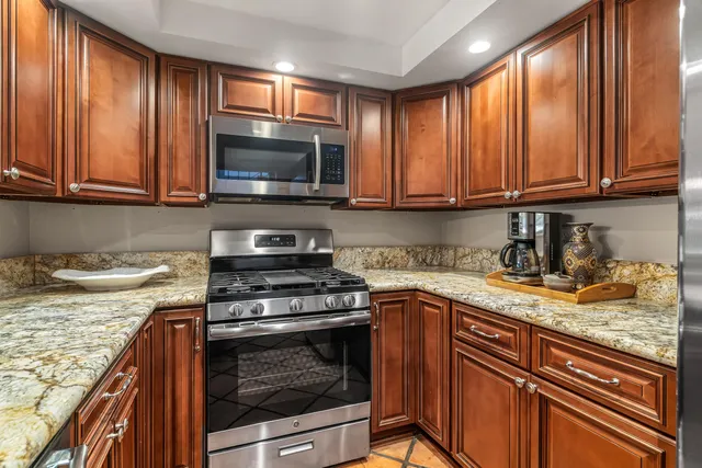 a kitchen with granite countertop wooden cabinets and a stove top oven
