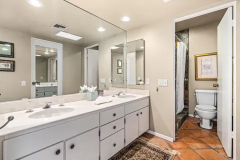 a spacious bathroom with a double vanity sink a toilet and a shower