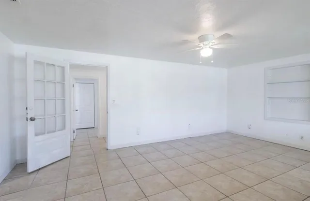 an empty room with white walls and ceiling fan