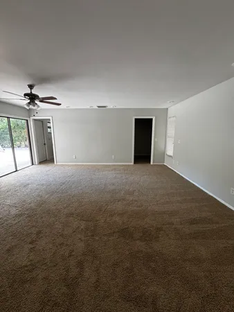 a view of a big room with windows and chandelier fan