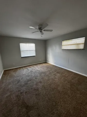 an empty room with windows and fan