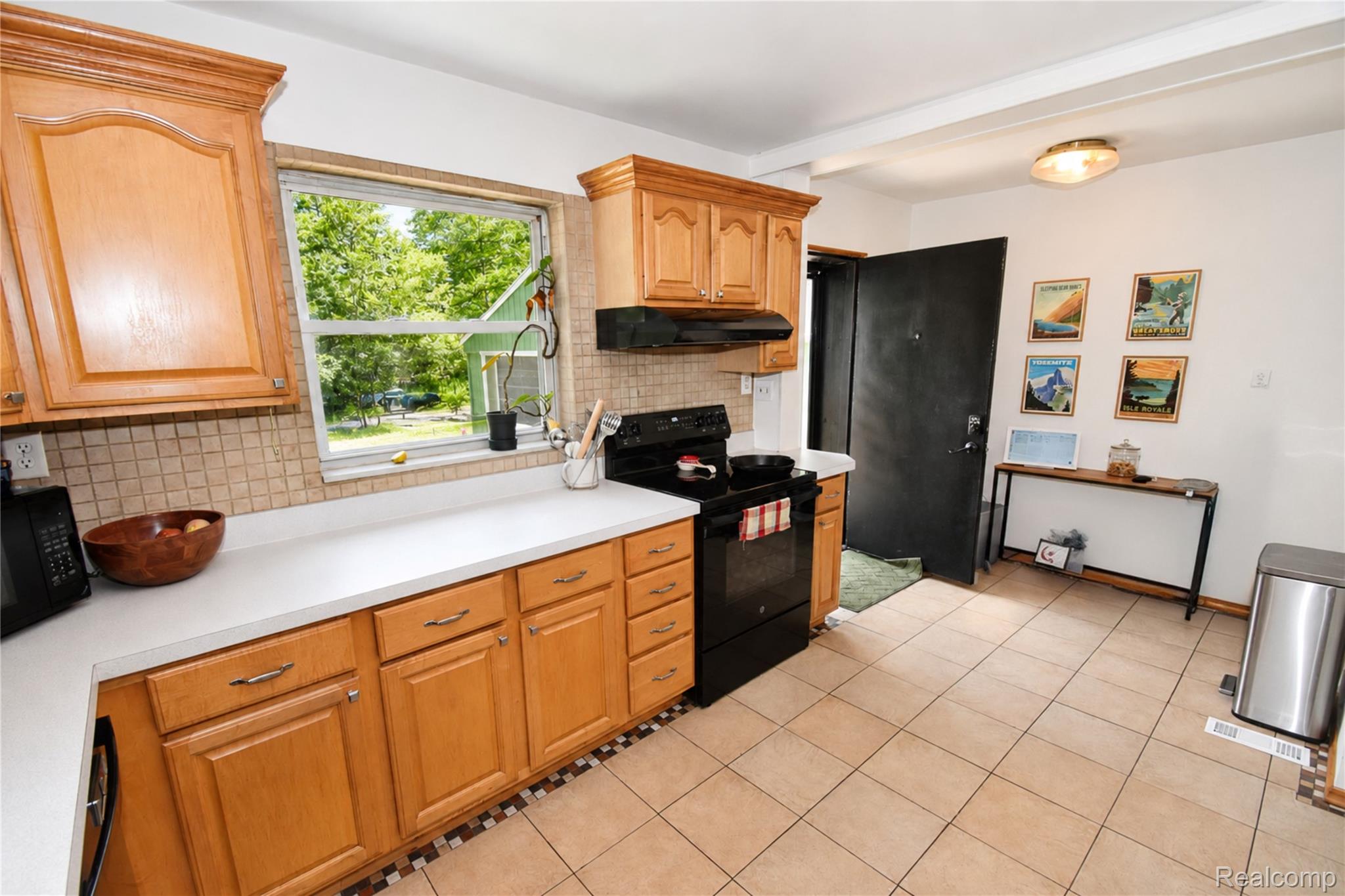 1405 Middle Road Highland, MI 48357 - Photo 6 of 18 Kitchen featuring blonde wood cabinetry, a light-toned countertop, and a tile backsplash