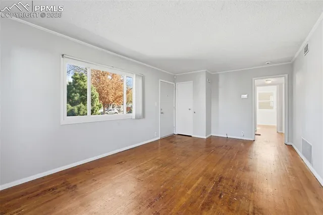 a view of an empty room with wooden floor and a window