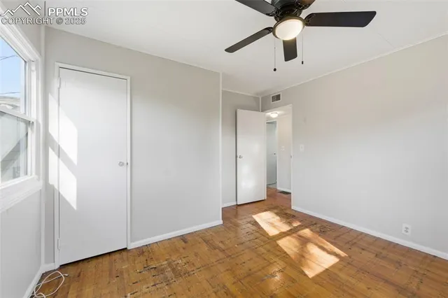 an empty room with a window and a ceiling fan