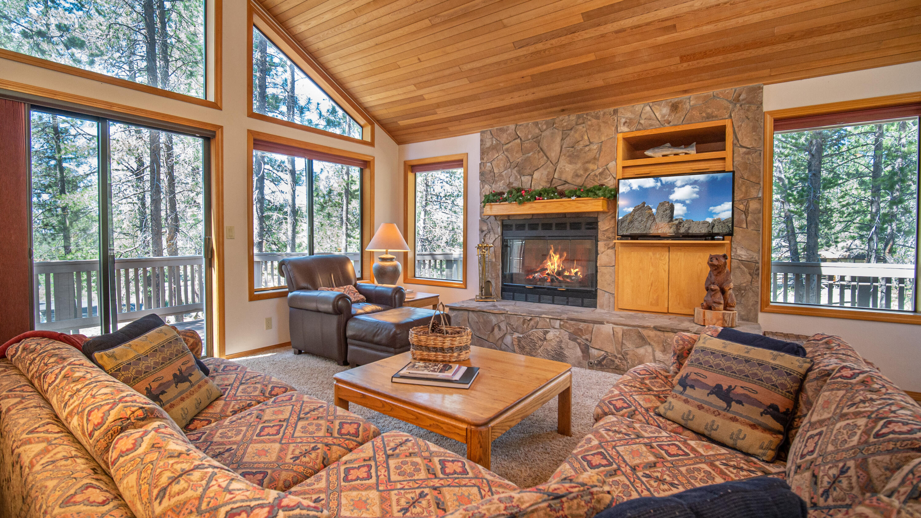 Floor-to-ceiling windows, vaulted, cedar-accented ceiling, stone fireplace and a Great Room concept create a classic Sunriver home.