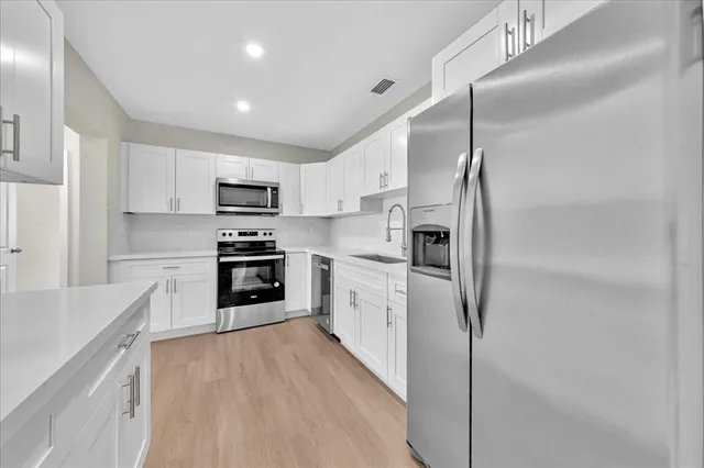 a kitchen with stainless steel appliances a refrigerator sink and microwave
