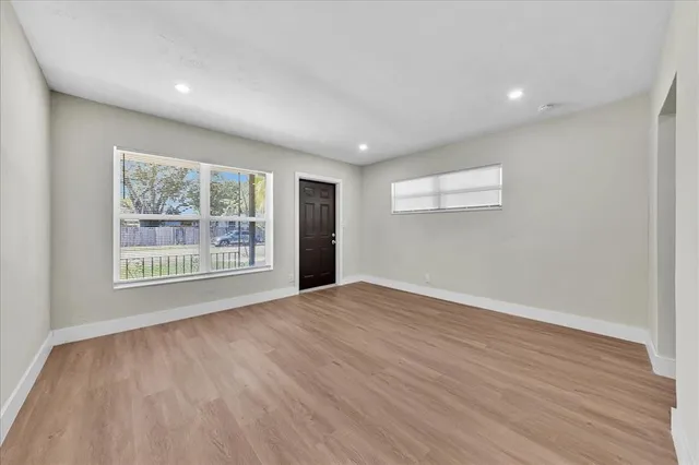 a view of an empty room with wooden floor and a window