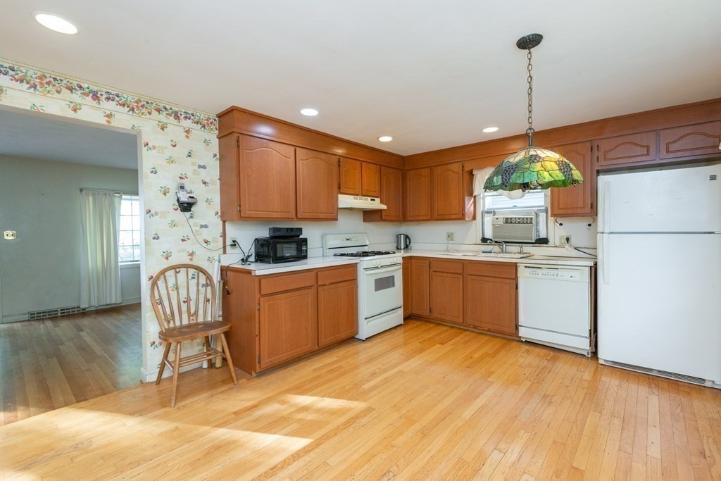 91 Brookside Road Lynn, MA 01902 - Photo 12 of 28 a kitchen with a refrigerator a stove top oven a sink dishwasher and white cabinets with wooden floor