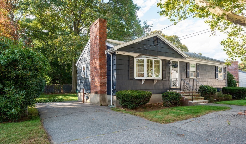 91 Brookside Road Lynn, MA 01902 - Photo 2 of 28 a view of a brick house next to a yard with plants and large trees