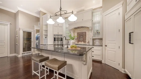 a large white kitchen with stainless steel appliances granite countertop a lot of counter space and wooden floors