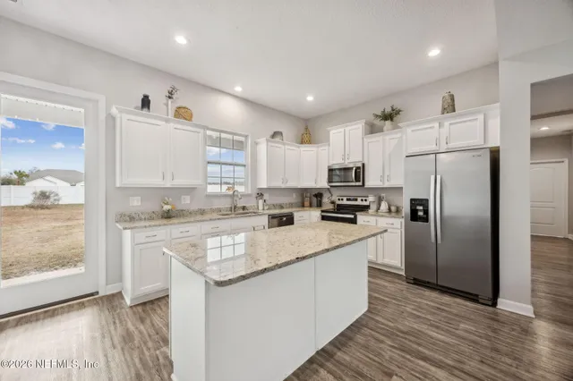 a kitchen with a sink dishwasher and white cabinets with wooden floor