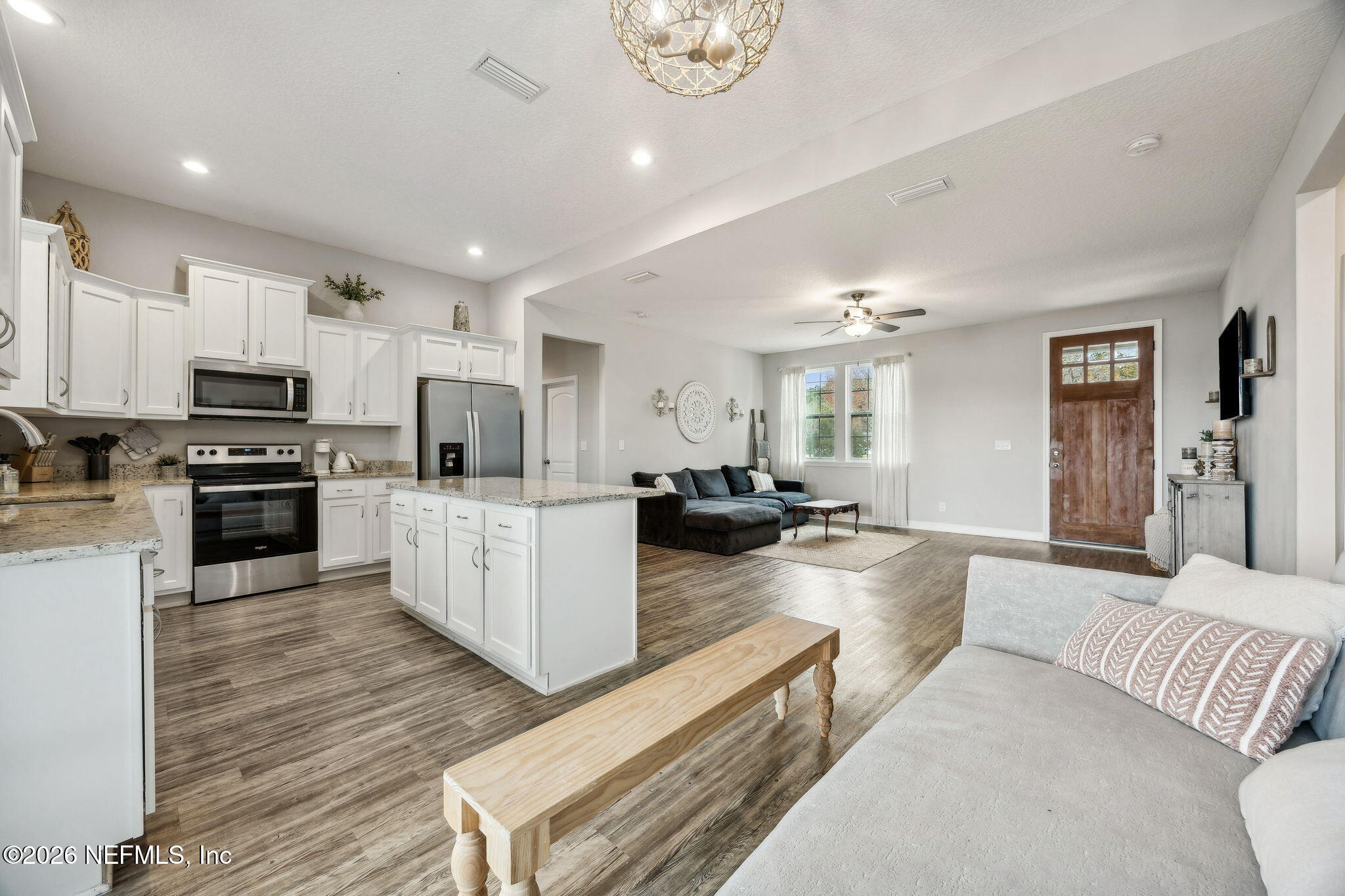 96718 Blackrock Road Yulee, FL 32097 - Photo 29 of 54 a large white kitchen with kitchen island a refrigerator a stove a sink dishwasher a oven with white cabinets and wooden floor