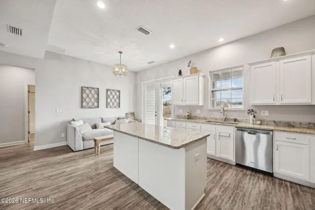 a kitchen with center island wooden floor and white cabinets