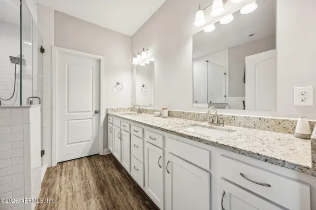 a bathroom with a granite countertop double vanity sink and mirror