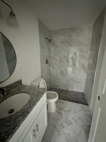 a bathroom with a granite countertop sink toilet and shower