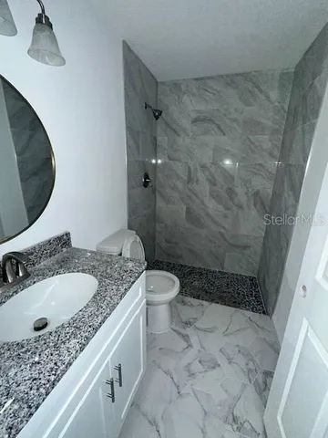 a bathroom with a granite countertop sink a toilet and shower