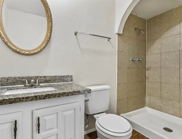 a bathroom with a granite countertop sink a toilet and a mirror