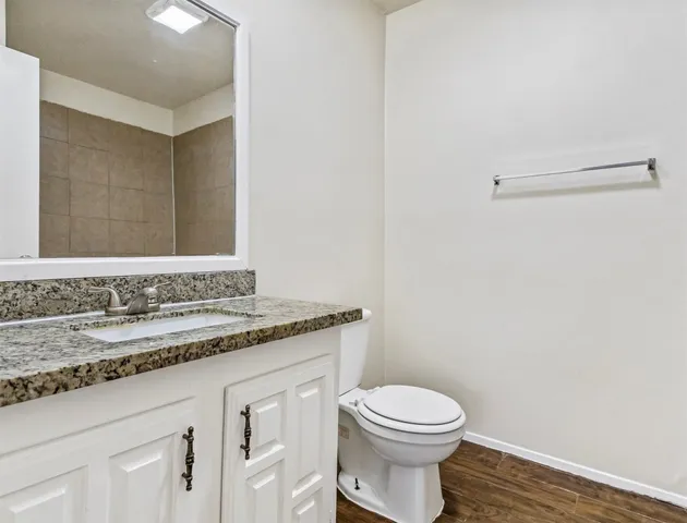 a bathroom with a granite countertop toilet sink and mirror