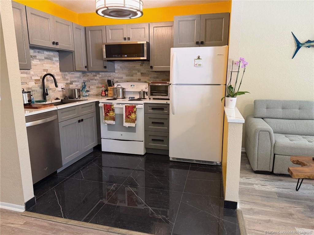 1225 Northwest 21st Street, Unit 3211 Stuart, FL 34994 - Photo 7 of 33 a white refrigerator freezer sitting inside of a kitchen with stainless steel appliances granite countertop wooden cabinets and a stove