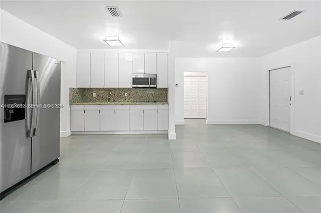 a view of kitchen with refrigerator cabinets and microwave