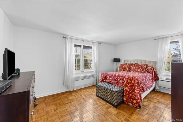 a bedroom with a bed and flat tv screen on the dresser