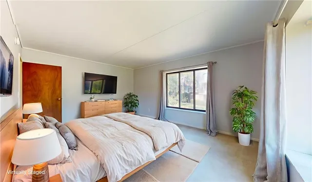 a spacious bedroom with a bed and a flat screen tv