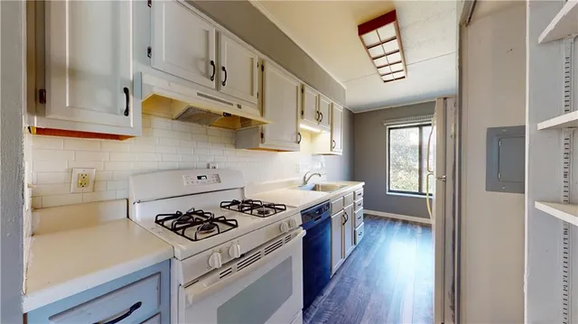 a kitchen with stainless steel appliances a stove a sink dishwasher and cabinets with wooden floor