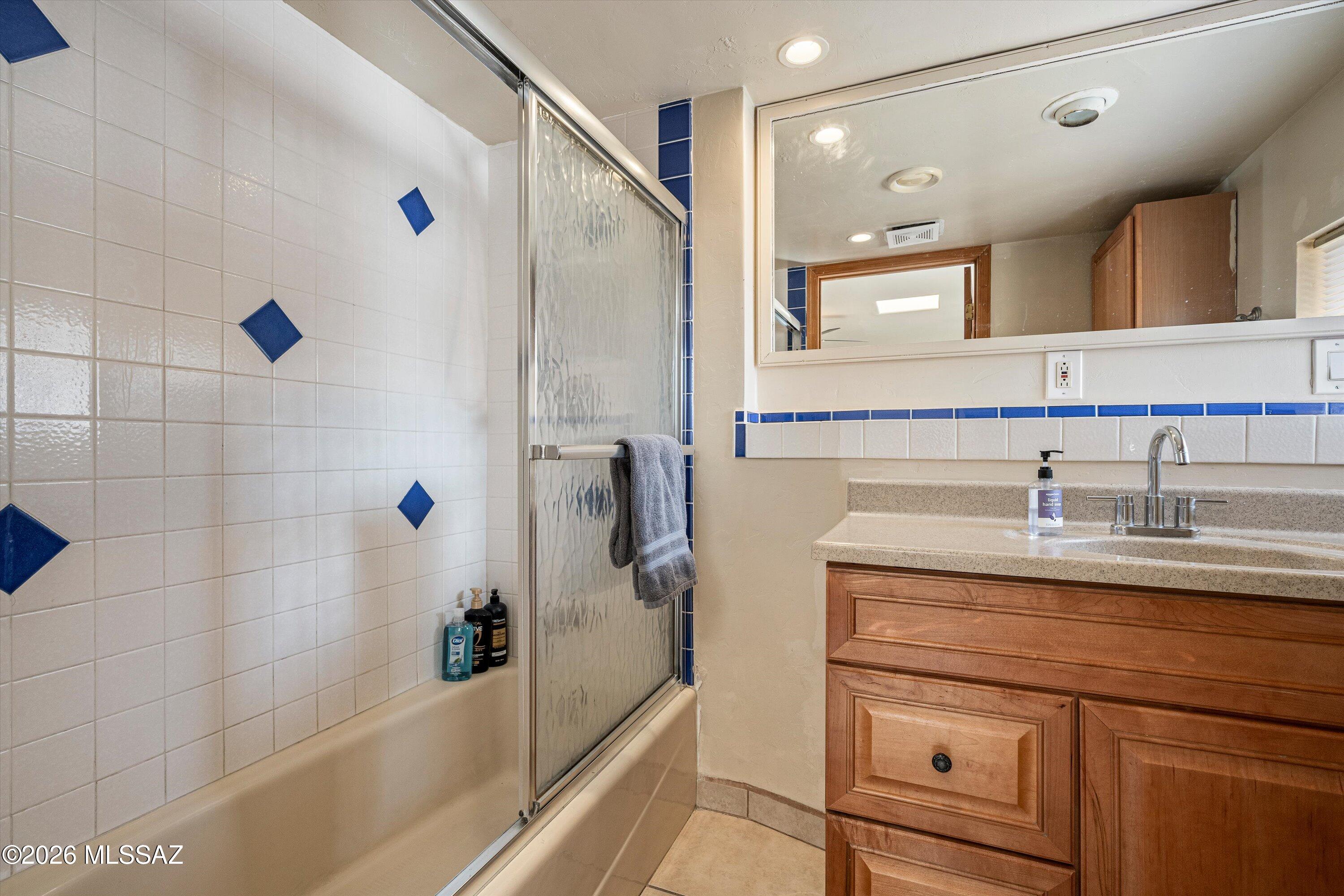 2619 East Prince Road Tucson, AZ 85716 - Photo 39 of 50 a bathroom with a granite countertop sink a mirror a bathtub and shower