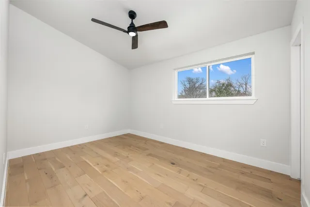 an empty room with wooden floor and ceiling fan