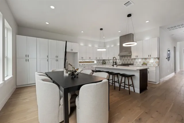 a kitchen with stainless steel appliances kitchen island granite countertop a table chairs sink and cabinets