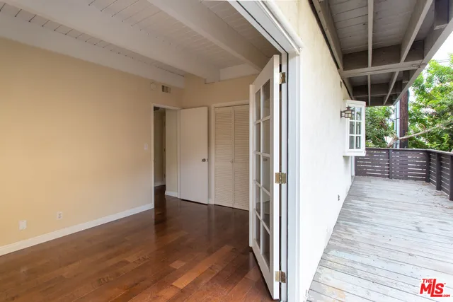 an empty room with wooden floor and windows with curtains