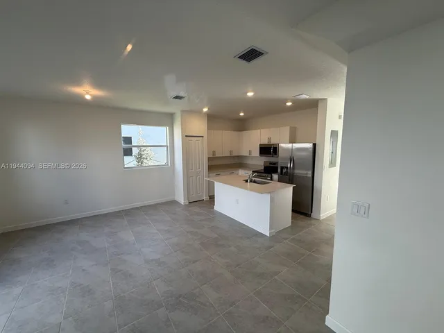 a view of kitchen with kitchen island stainless steel appliances refrigerator sink and cabinets