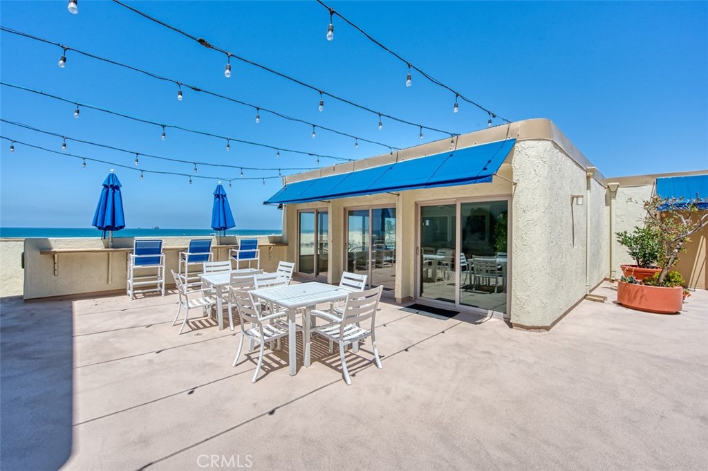 711 Pacific Coast Highway, Unit 421 Huntington Beach, CA 92648 - Photo 29 of 35 a view of a patio with dining table and chairs under an umbrella