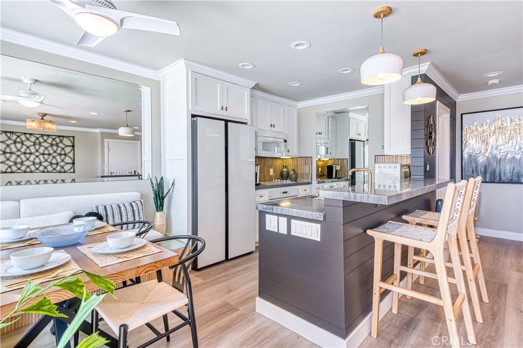 711 Pacific Coast Highway, Unit 421 Huntington Beach, CA 92648 - Photo 4 of 35 a kitchen with granite countertop kitchen island stainless steel appliances a table and chairs in it