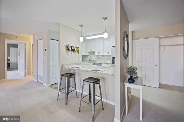 a kitchen with kitchen island a dining table chairs stainless steel appliances and cabinets