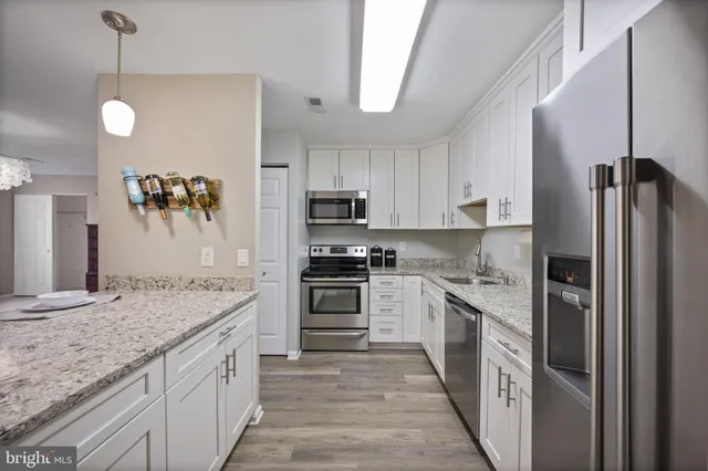 a kitchen with stainless steel appliances granite countertop a refrigerator a stove and a sink