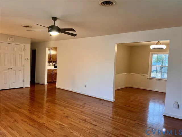 a view of an empty room with window and wooden floor
