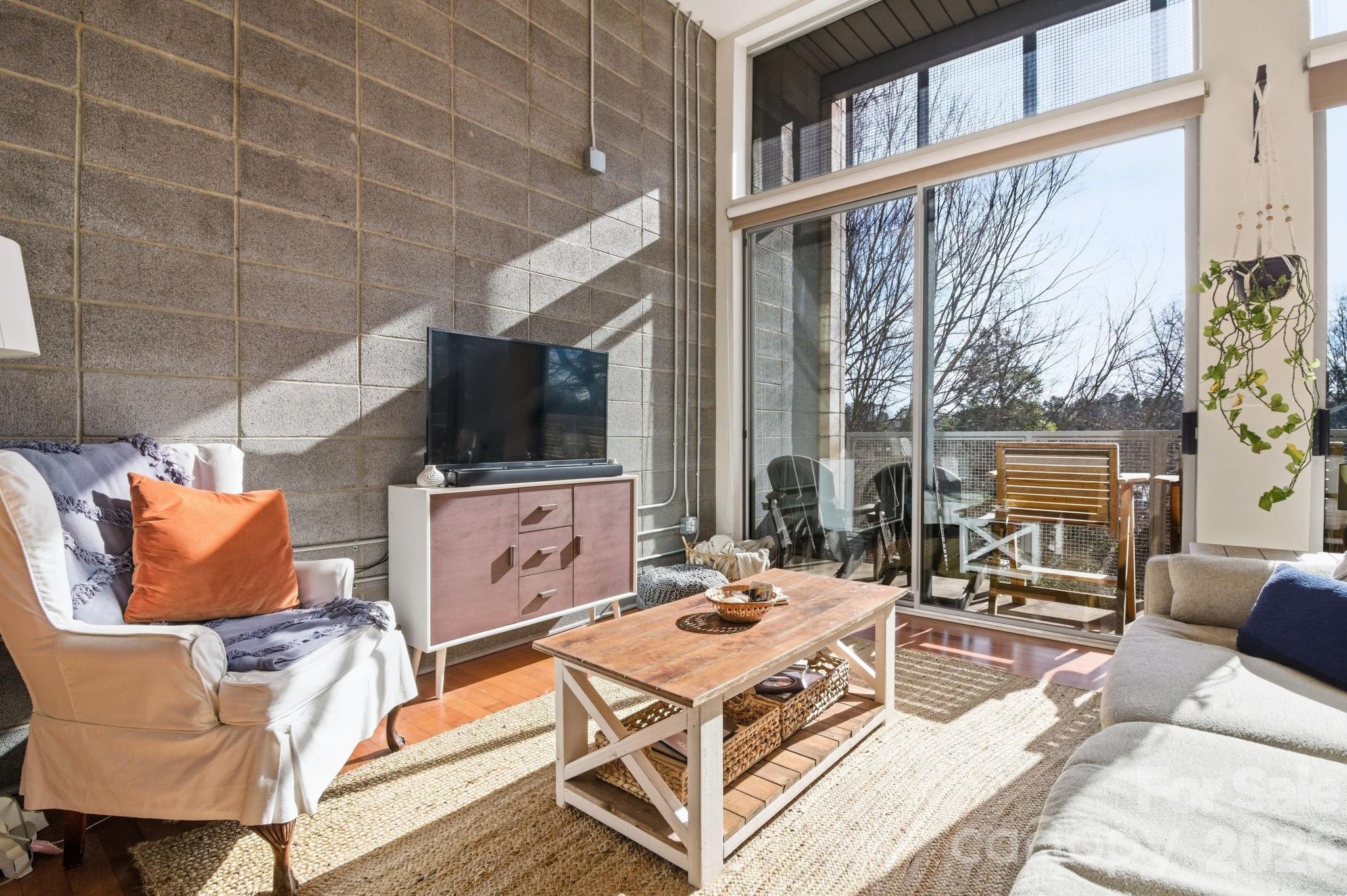2116 McClintock Road, Unit 123 Charlotte, NC 28205 - Photo 2 of 28 a living room with furniture a flat screen tv and a floor to ceiling window