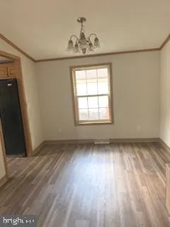 an empty room with wooden floor cabinet and windows