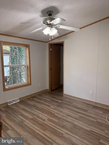 an empty room with wooden floor chandelier and windows