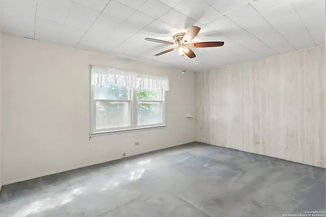 an empty room with windows and fan