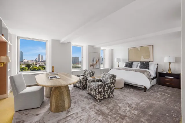 a spacious bedroom with a bed a couch and a potted plant