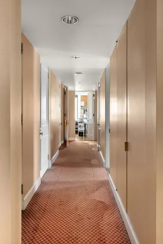 a view of a hallway with wooden floor and a bathroom