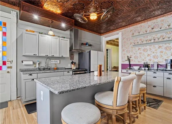 a kitchen with stainless steel appliances kitchen island granite countertop a refrigerator and a wooden cabinets